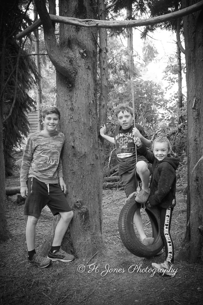 Monochrome siblings playing with tyre swing
