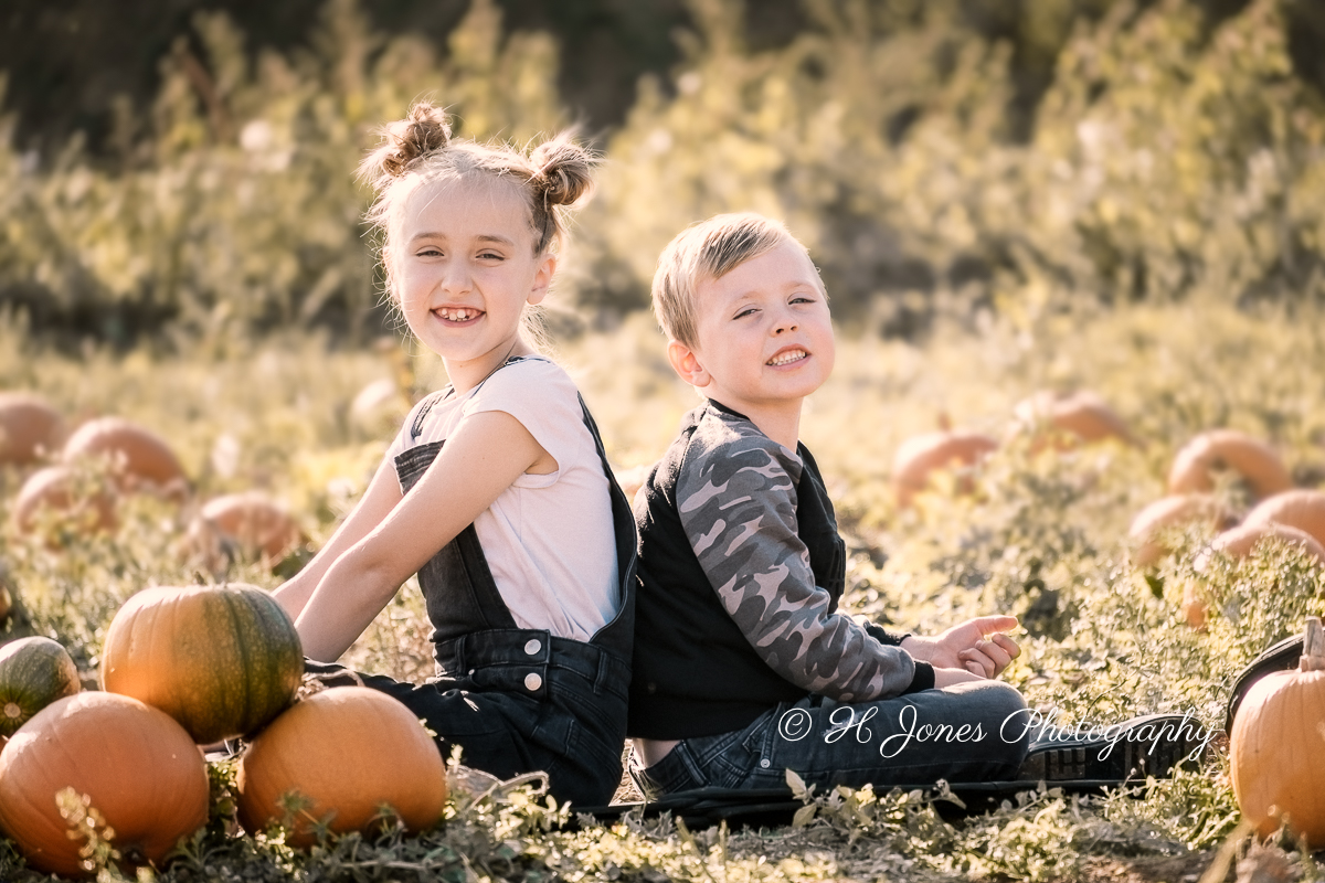 Children smiling in a pumpkin field