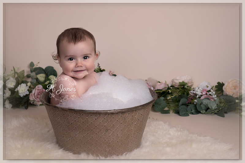 one year old girl in vintage tin bath with lots of bubbles after cake smash photoshoot