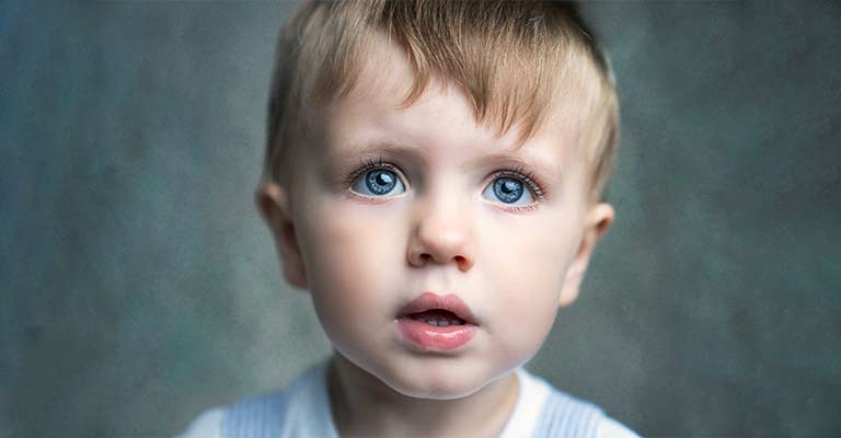 Close up portrait of a young boy's face, with bright blue eyes.