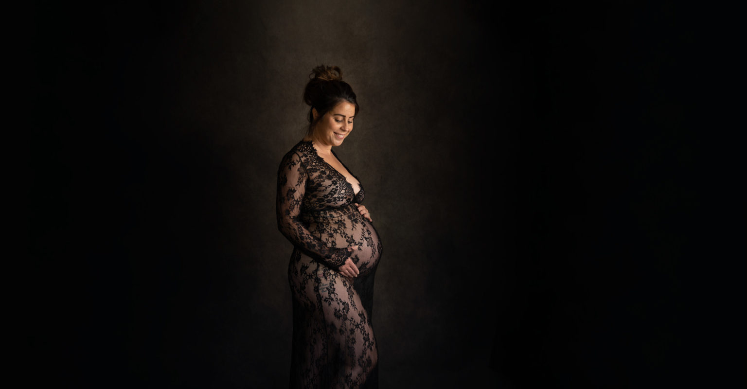 Mother-to-be smiling while holding baby bump during a Hampshire pregnancy photographer session