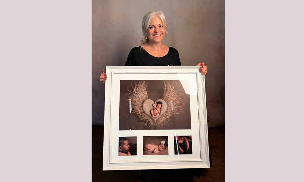 Helen Jones of H Jones Photography in her Hampshire photography studio holding a large framed print from a newborn baby photoshoot.