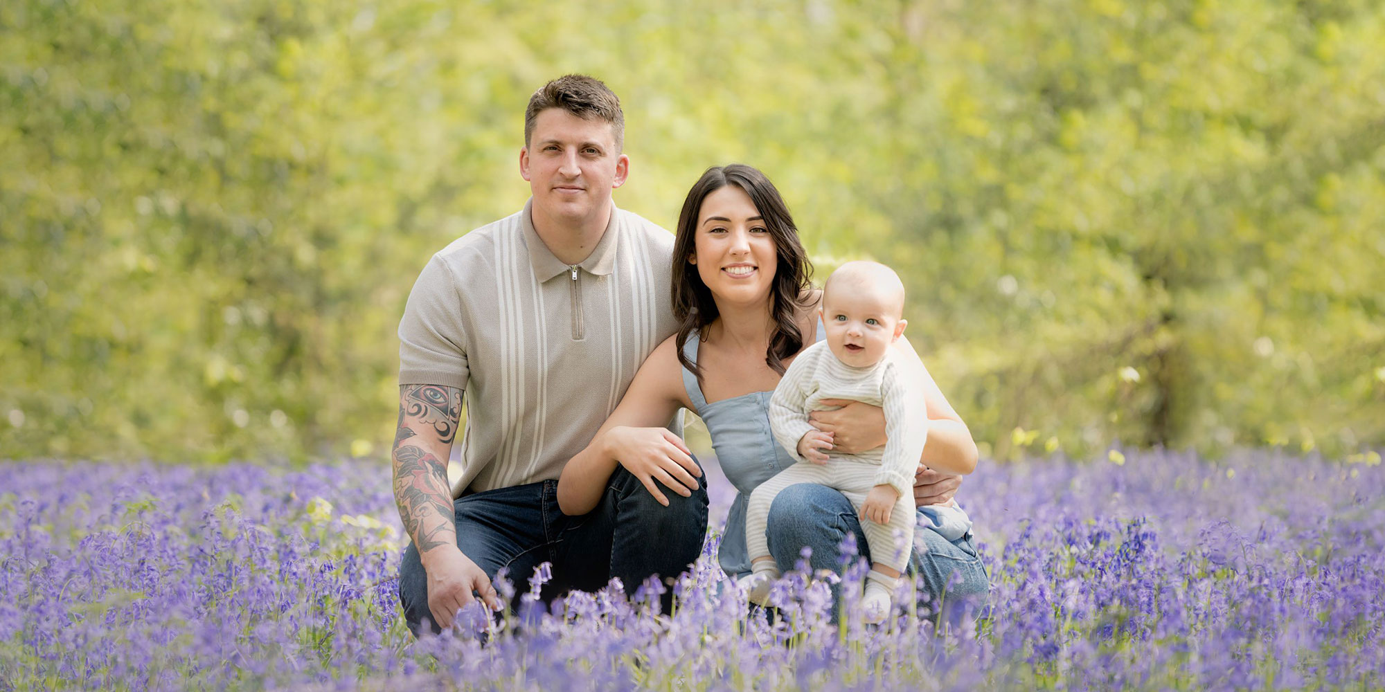 Young family crouched in the bluebell woods in Hampshire.
