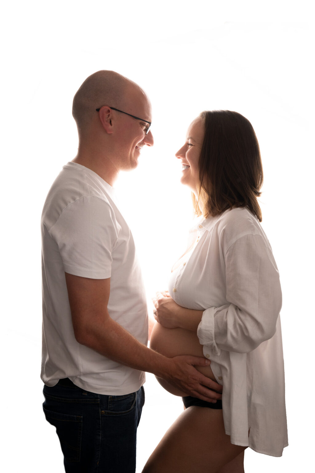 Young couple expecting a baby posing face to face, bump exposed.
