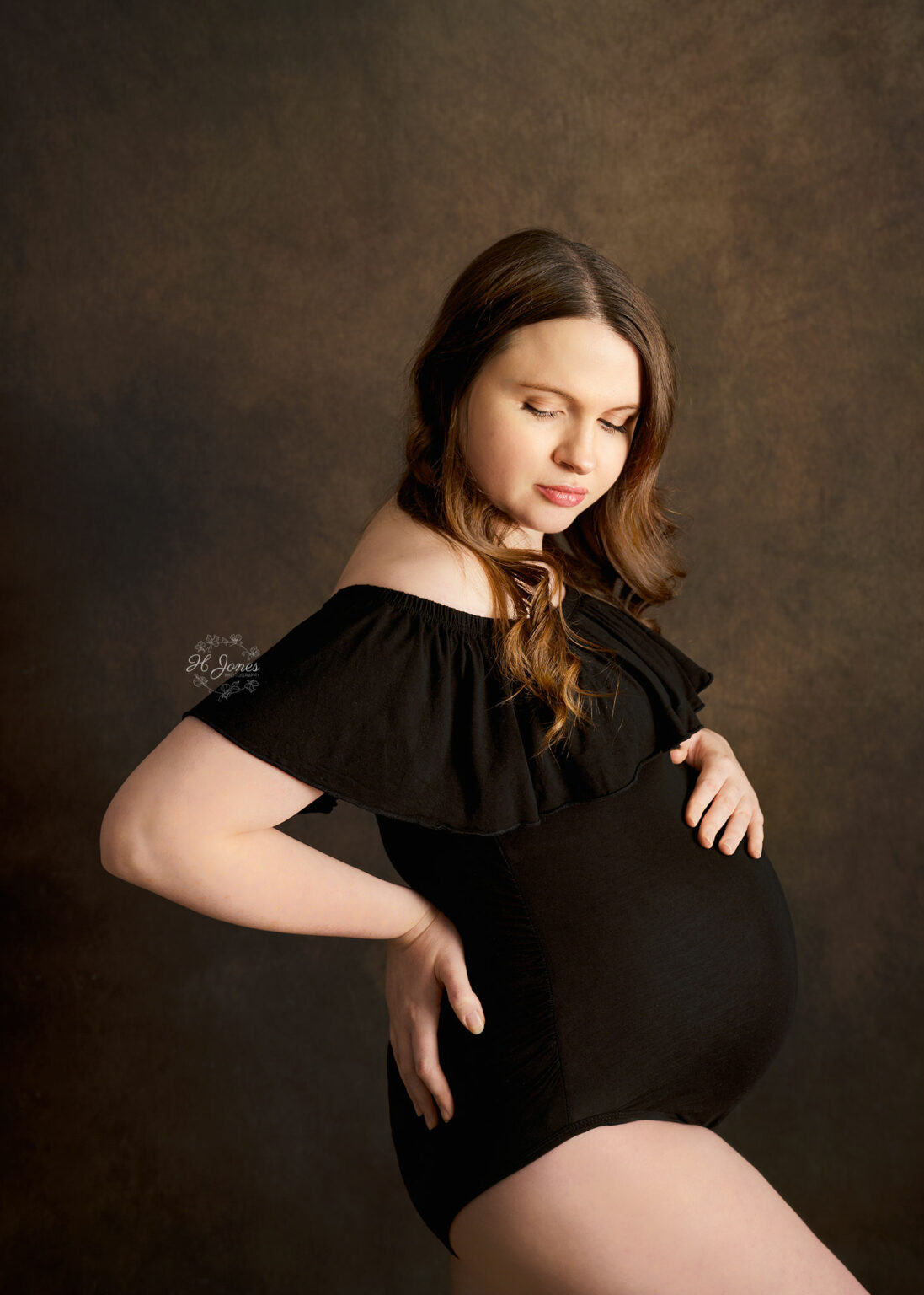 Timeless image of pregnant woman posing in a black maternity bodysuit.