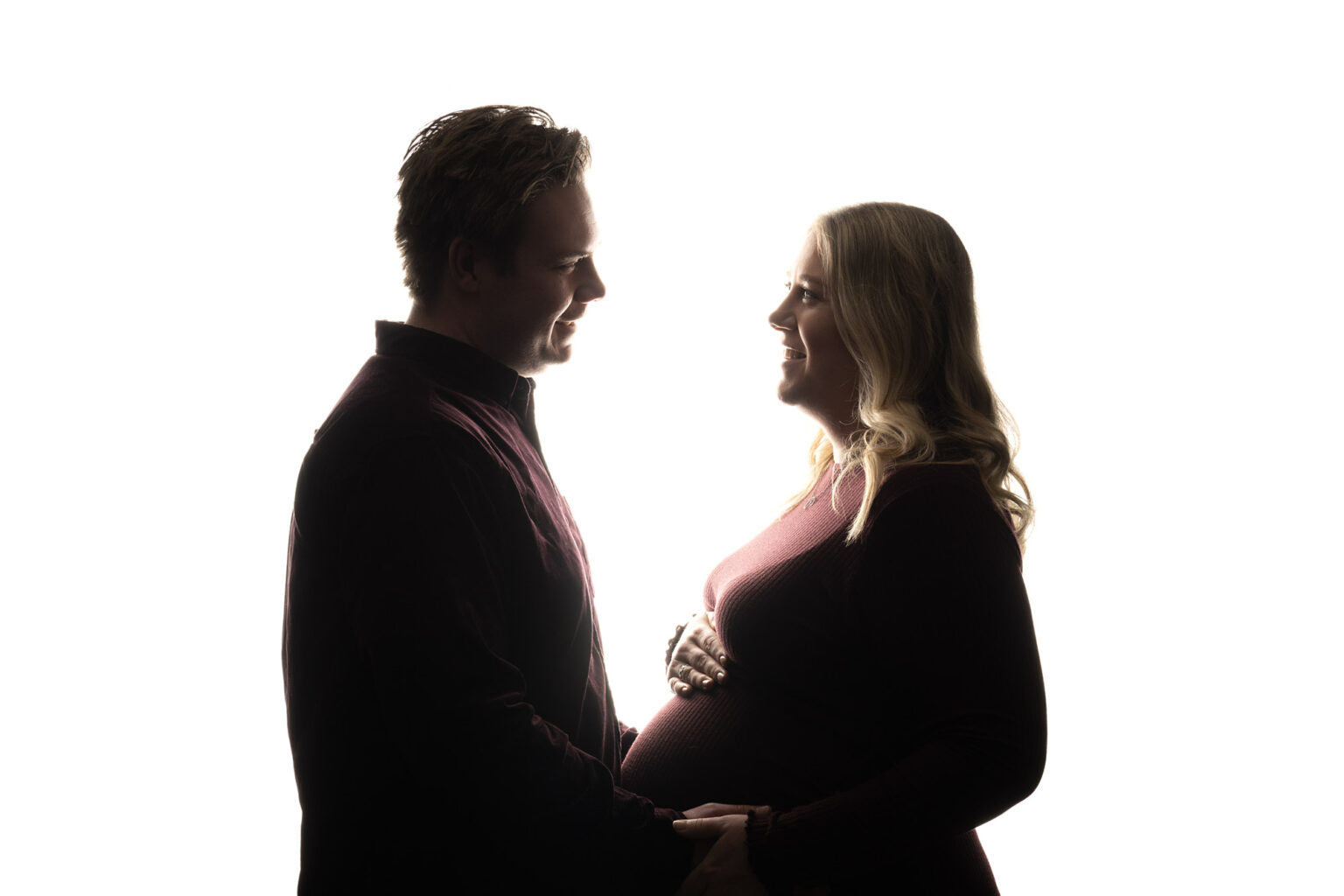 Backlit pregnant couple, smiling at each other