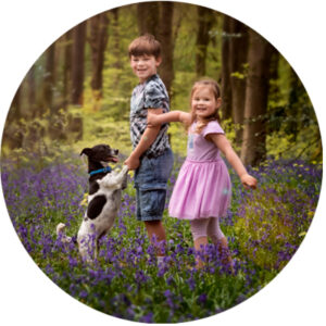 Photo of two children and a Jack Russell dog, playing in the Hampshire bluebell woods.