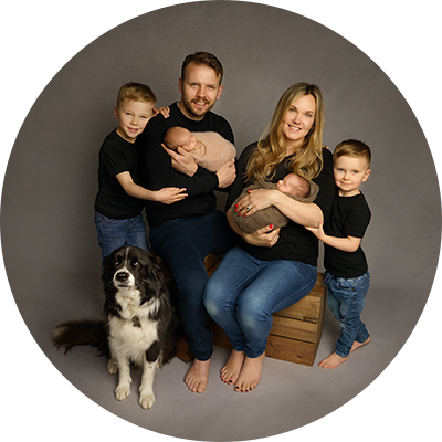 Family of 6, all wearing black t-shirts, with newborn twins, posing with sheepdog.