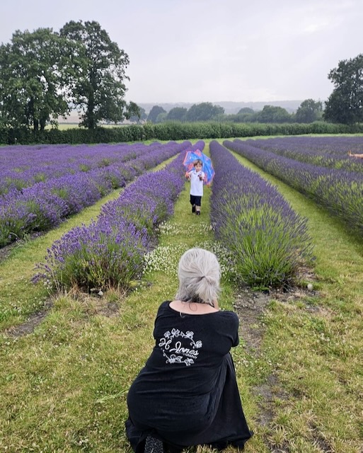 Helen Jones crouching down taking a photo of a young boy running through the lavender fields.