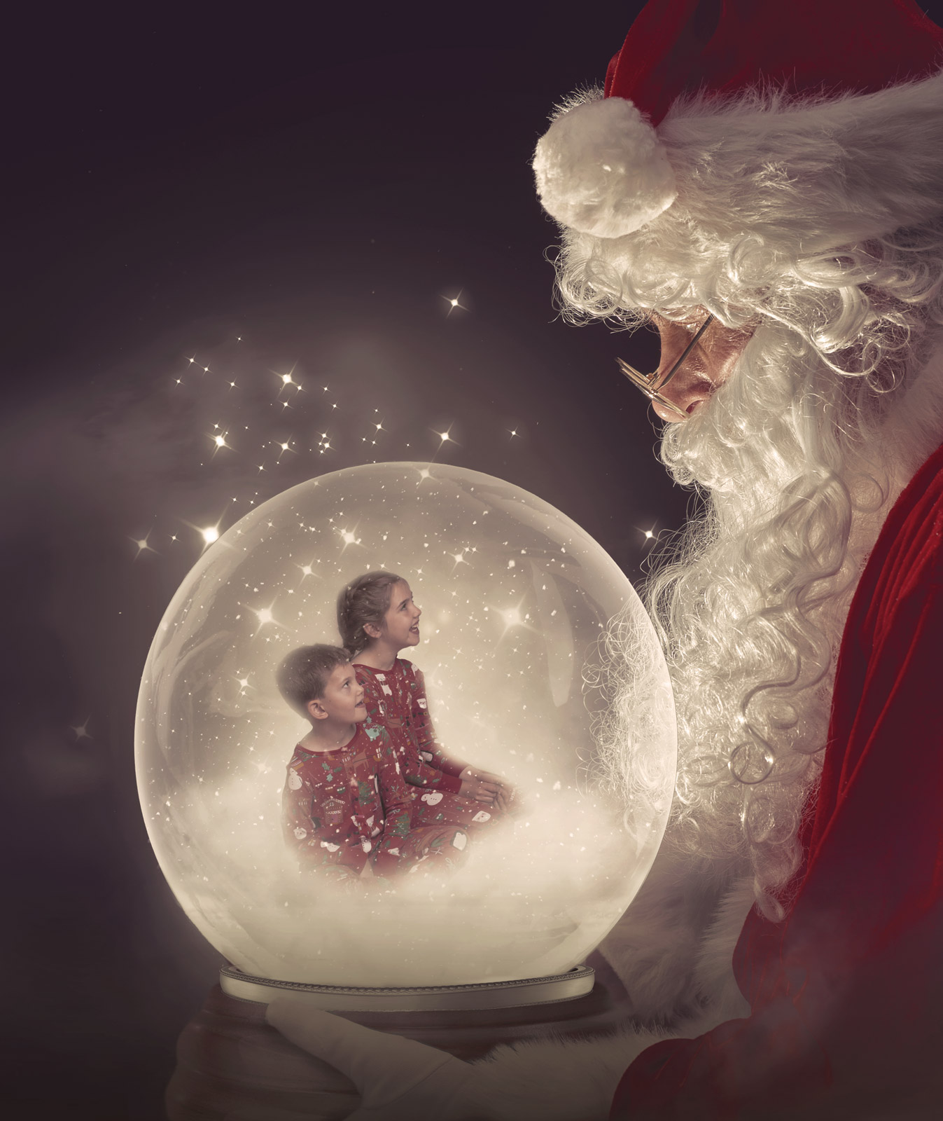 Brother and sister sitting inside a snow globe held by Santa at a Christmas Photoshoot in Hampshire