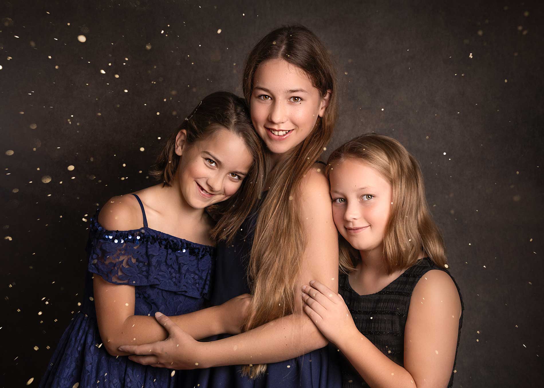 Three sisters dressed on navy blue at a Christmas photoshoot in Hampshire