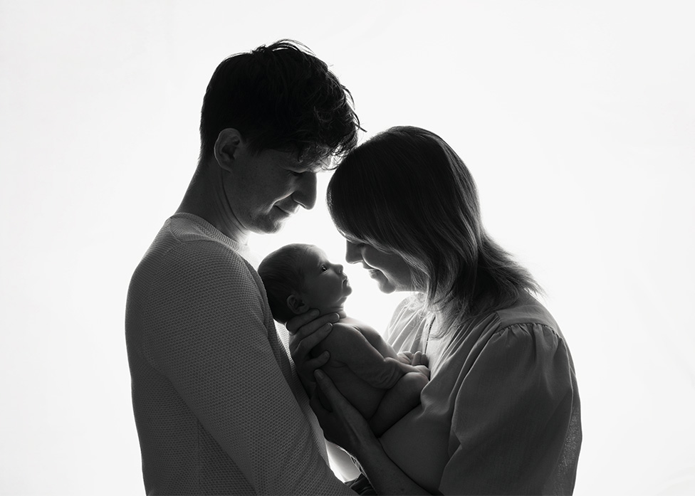 Black and white portrait of parents with newborn baby