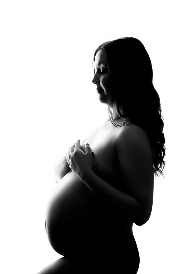 Black and white backlit portrait of pregnant woman