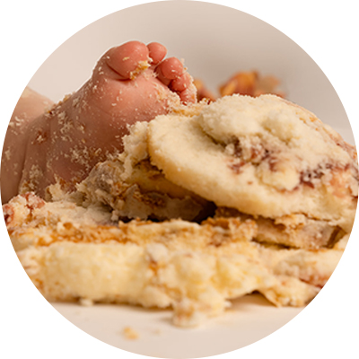 Close up image of a baby's foot in amongst cake icing and crumbs at a cake smash photoshoot in Andover.