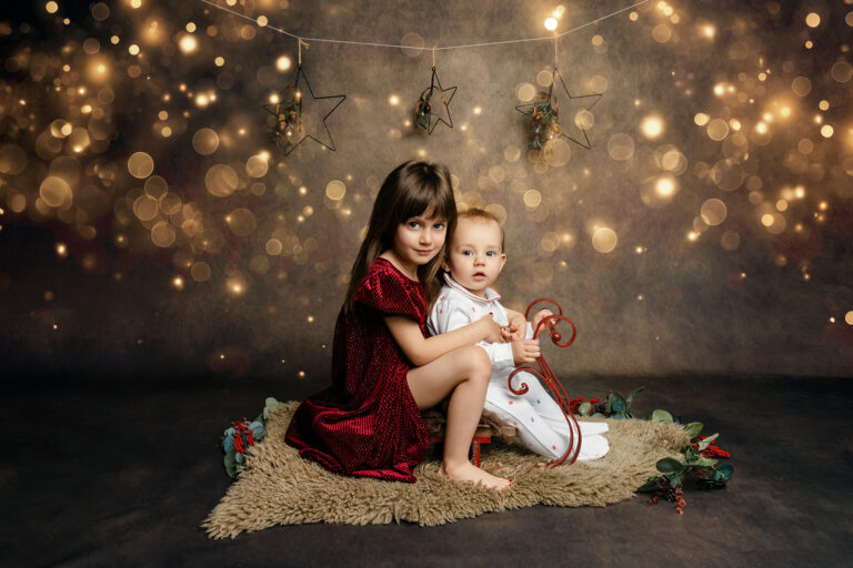 Brother and sister on a small sleigh at H Jones Photography Christmas mini session.