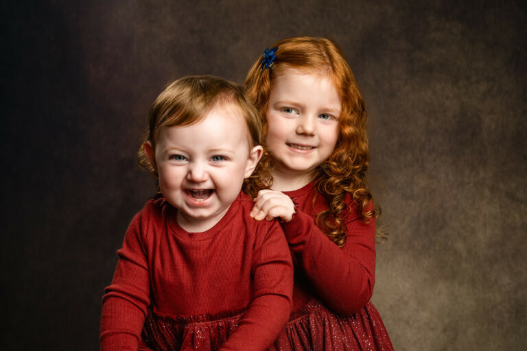 Two sisters wearing red Christmas dresses at a photoshoot near Andover.