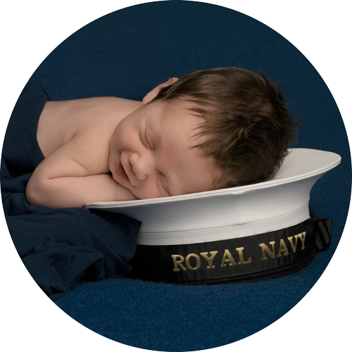 Newborn baby sleeping peacefully on a Royal Navy hat during a professional newborn photoshoot in Hampshire, capturing a meaningful and timeless portrait.