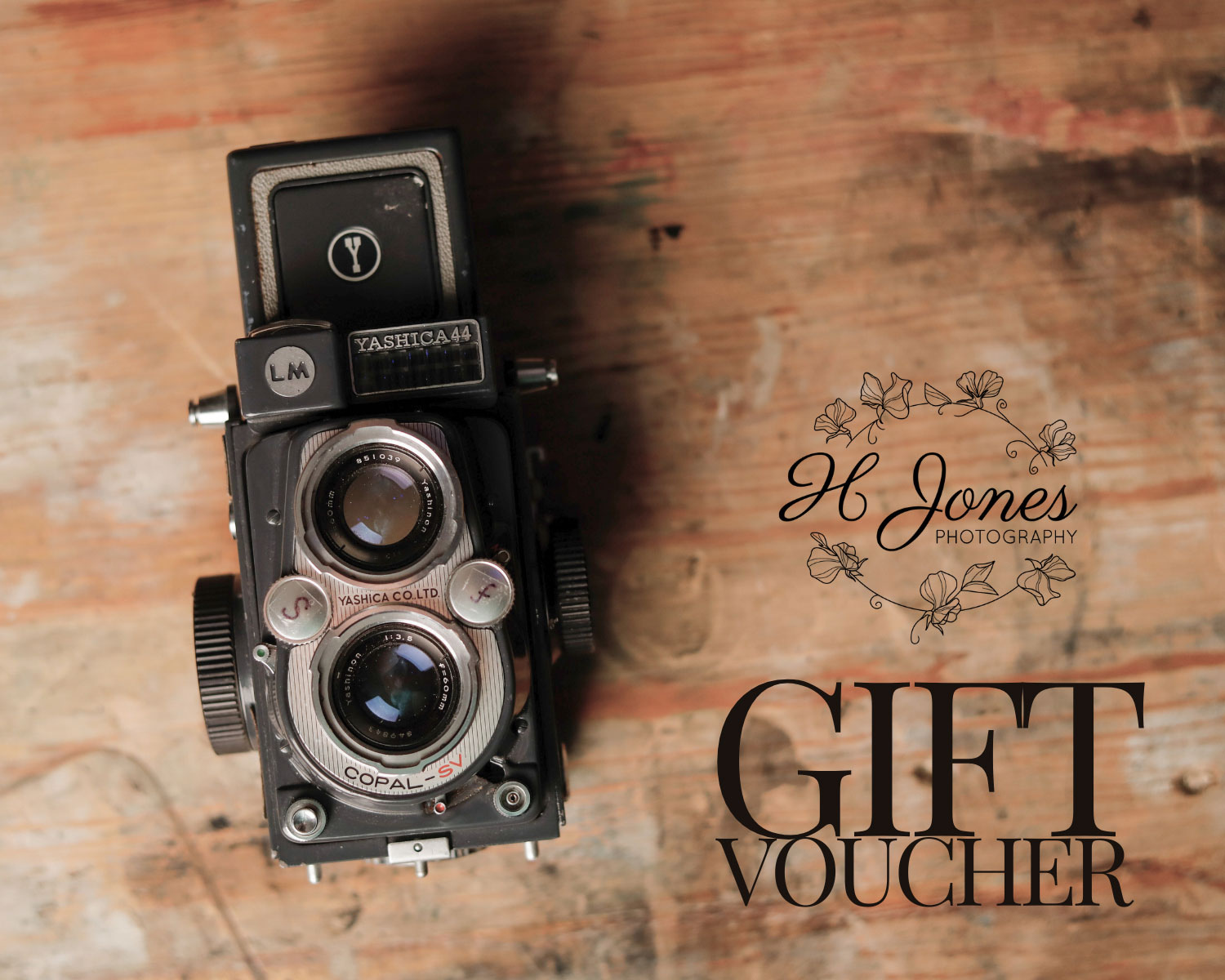Photo of a vintage camera on a wooden table with the text gift voucher from H Jones Photography Hampshire.