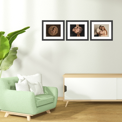 A bright, modern living room featuring three framed newborn and family portraits on the wall, showcasing professional photography by a Hampshire newborn photographer.