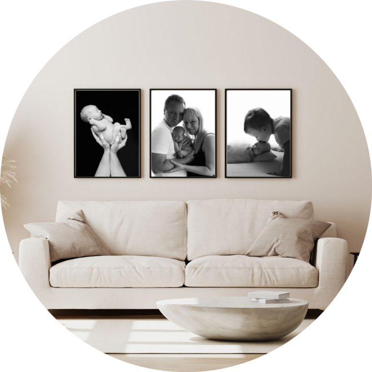 Set of three black and white framed newborn and family portraits displayed as wall art above a sofa in a bright, neutral living room, showcasing timeless baby photography by a Hampshire newborn photographer.