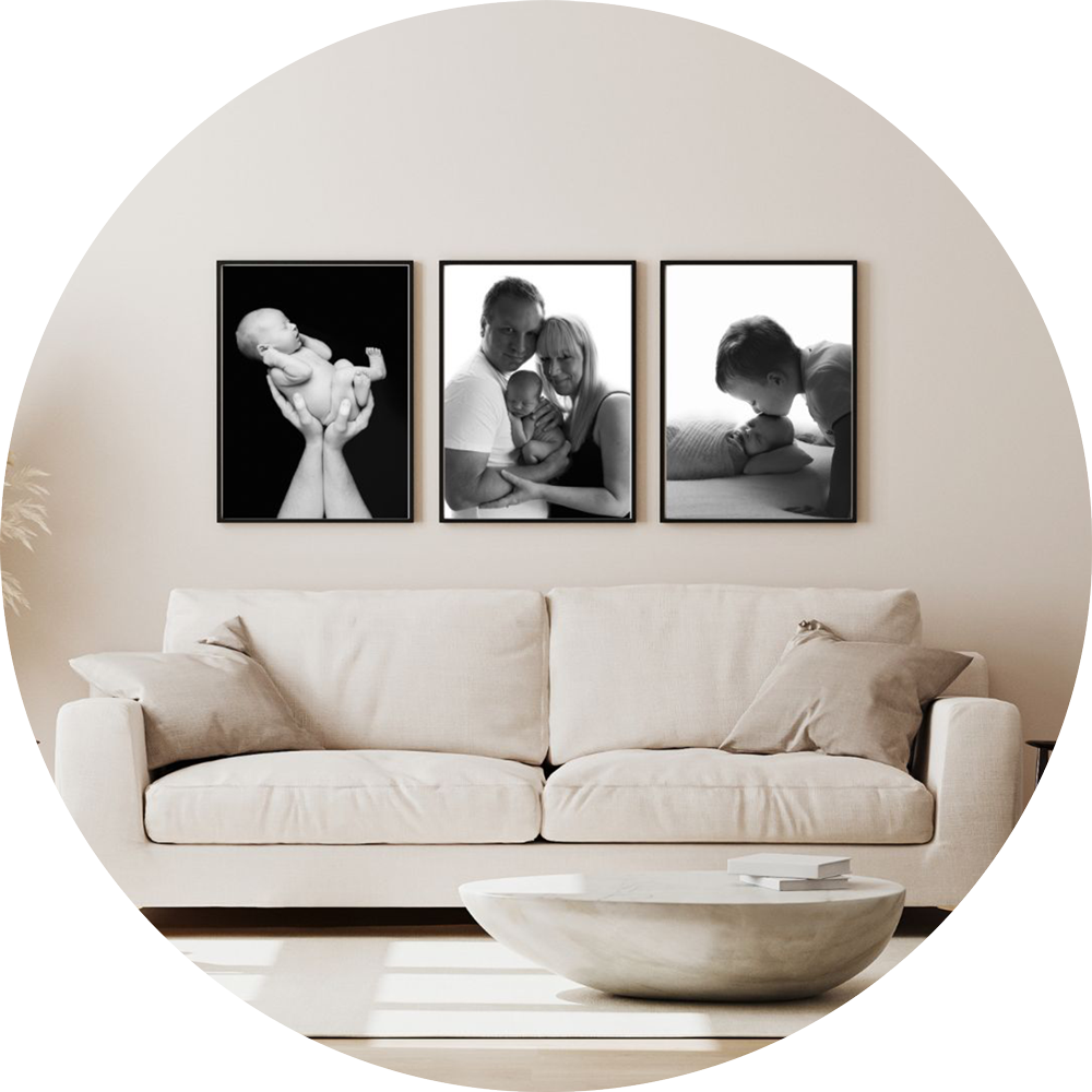 Set of three black and white framed newborn and family portraits displayed as wall art above a sofa in a bright, neutral living room, showcasing timeless baby photography by a Hampshire newborn photographer.