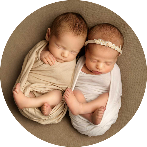 Sleeping newborn twins wrapped in soft neutral fabrics, photographed in a natural, timeless style at a Hampshire newborn photography studio.
