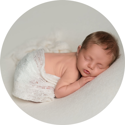Sleeping newborn baby wrapped in soft white knit blanket during a natural newborn photoshoot in Andover, Hampshire studio