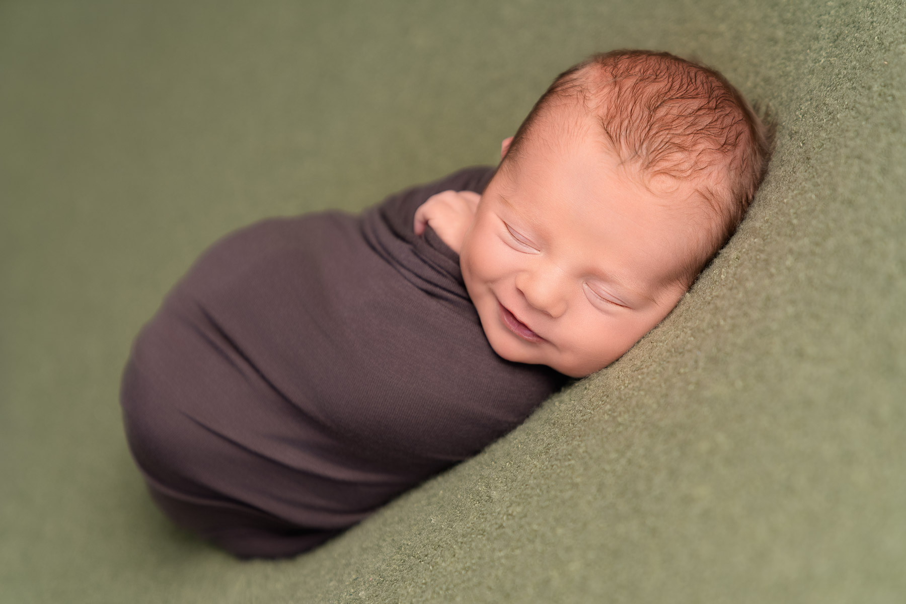 Newborn baby Albie sleeping peacefully wrapped in soft fabric during a studio newborn photography session in Anna Valley near Andover, Hampshire