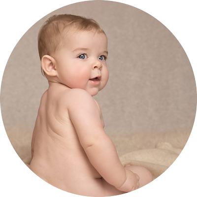 Natural sitter session portrait of baby sitting and looking over shoulder on a neutral backdrop at a studio near Andover, Hampshire.