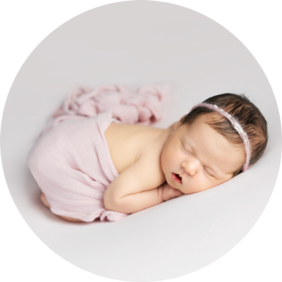 Sleeping newborn baby wrapped in soft pink fabric with headband, photographed in a natural, minimal studio style near Andover, Hampshire