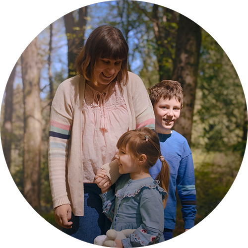 Mum with two children standing holding hands in a woodland photoshoot near Andover, Hampshire.