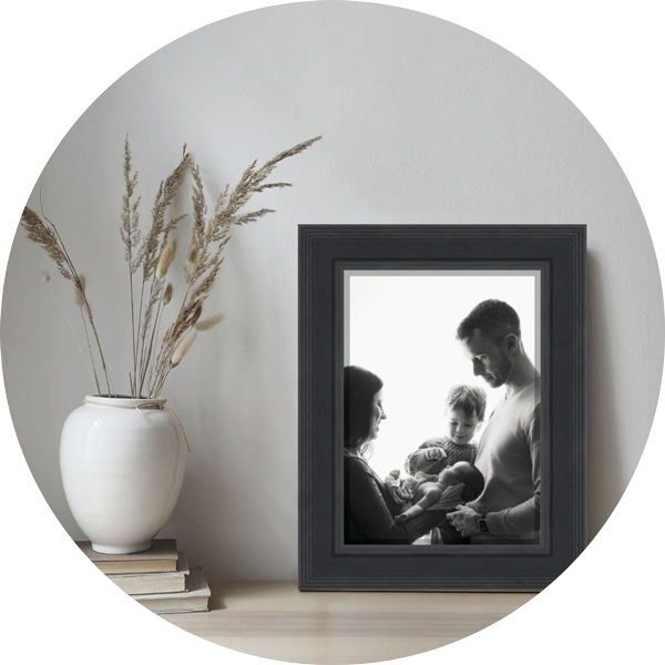 Framed black and white newborn family portrait displayed as wall art, featuring parents, sibling and new baby, created by a Hampshire newborn photographer serving Andover and surrounding areas.