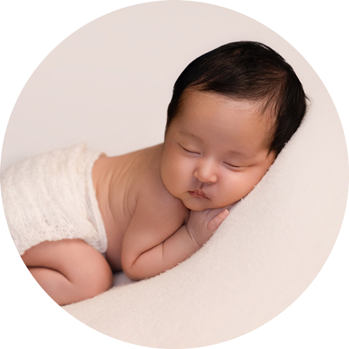 Peacefully sleeping newborn baby posed on a soft cream backdrop during a professional newborn photography session near Basingstoke, photographed by a Hampshire newborn photographer.