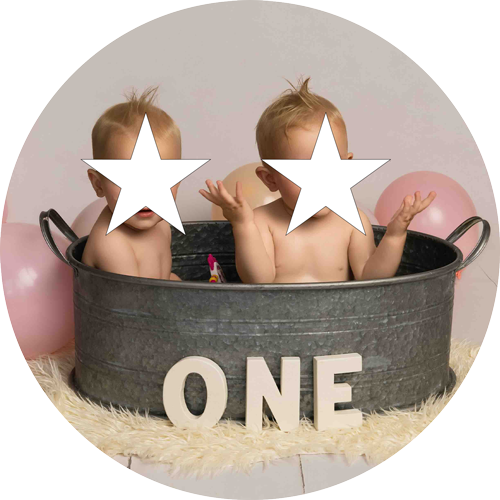 Twin babies enjoying a cake smash and splash photoshoot in a rustic metal bath at H Jones Photography's studio near Andover, Hampshire.