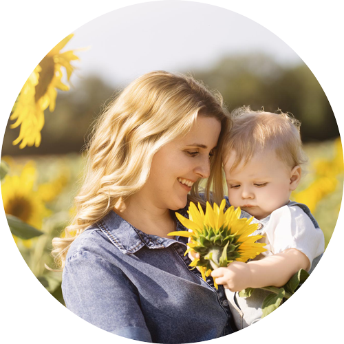 Mother cuddling her baby during a sunflower mini photoshoot in Hampshire by H Jones Photography.