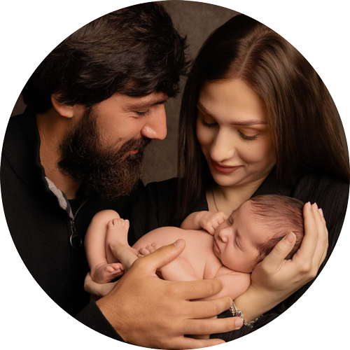 Parents cradling their sleeping newborn baby during a family photoshoot.