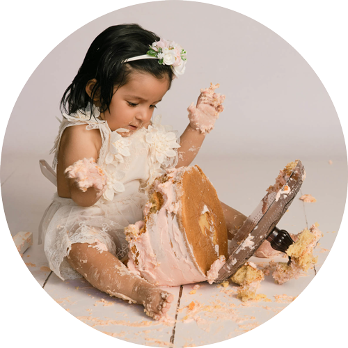 Baby girl enjoying her first birthday cake smash with pink cake