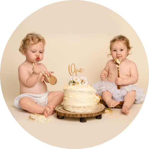 Twin babies enjoying their first birthday cake smash together